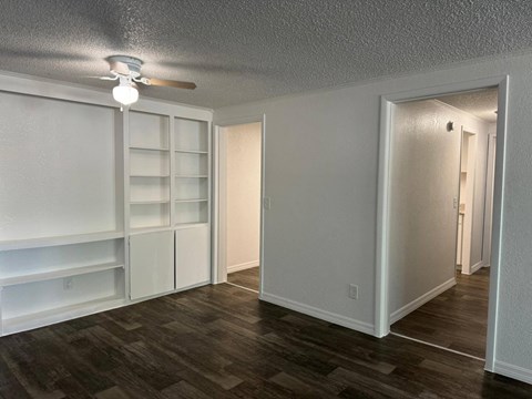 a living room with white shelves and a ceiling fan